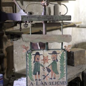 Enseigne ancienne peinte montrant deux personnages encadrant une étoile, avec l’inscription « À l’enseigne des bons enfants ».