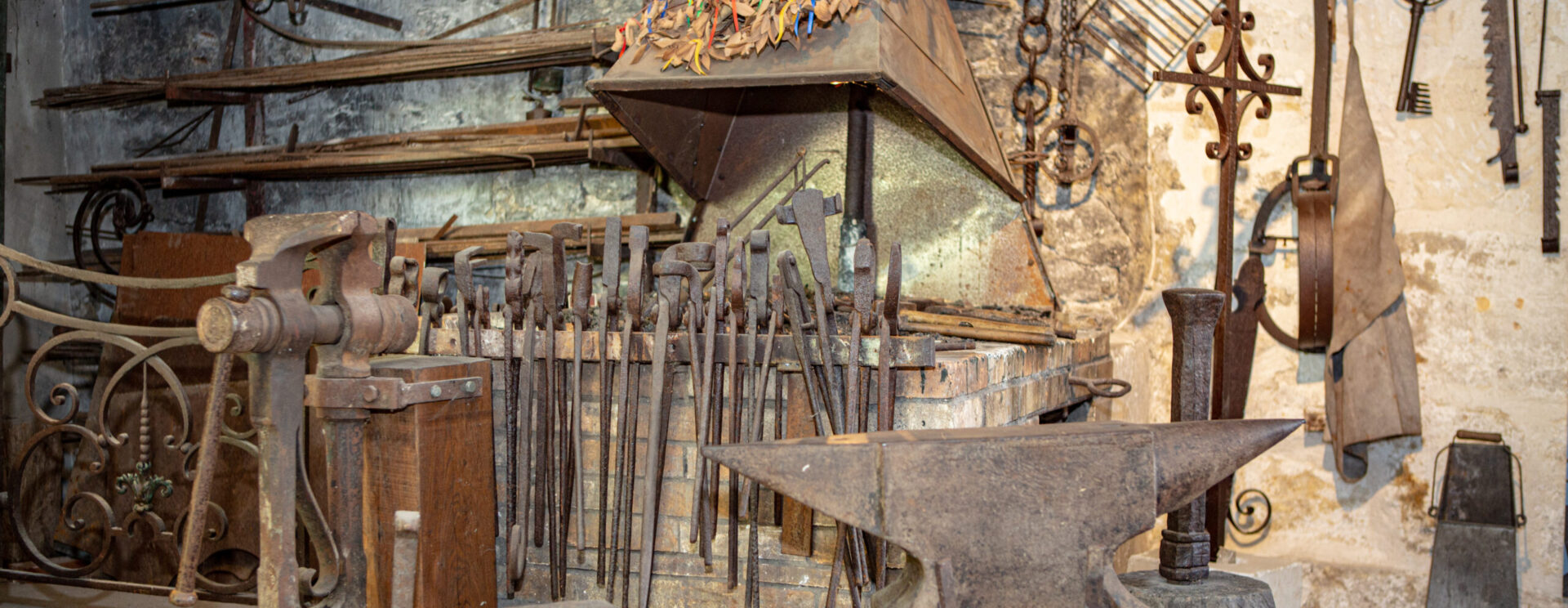 un atelier de type forge avec plusieurs outils anciens comme des enclumes ou des pinces de couleur marron