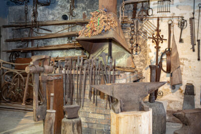 un atelier de type forge avec plusieurs outils anciens comme des enclumes ou des pinces de couleur marron - Agrandir l'image 2 sur 6, fenêtre modale