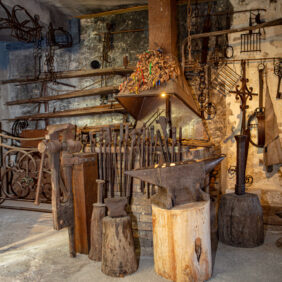 un atelier de type forge avec plusieurs outils anciens comme des enclumes ou des pinces de couleur marron