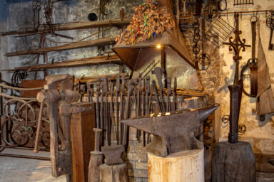 un atelier de type forge avec plusieurs outils anciens comme des enclumes ou des pinces de couleur marron