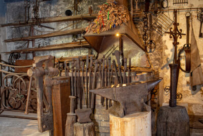un atelier de type forge avec plusieurs outils anciens comme des enclumes ou des pinces de couleur marron - Agrandir l'image 1 sur 6, fenêtre modale