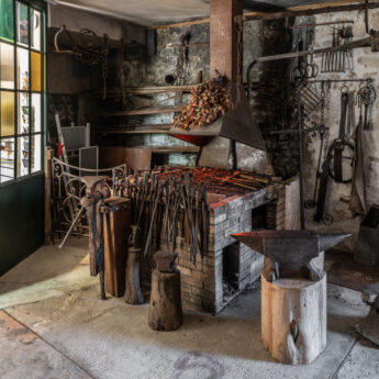 un atelier de type forge avec plusieurs outils anciens comme des enclumes ou des pinces de couleur marron